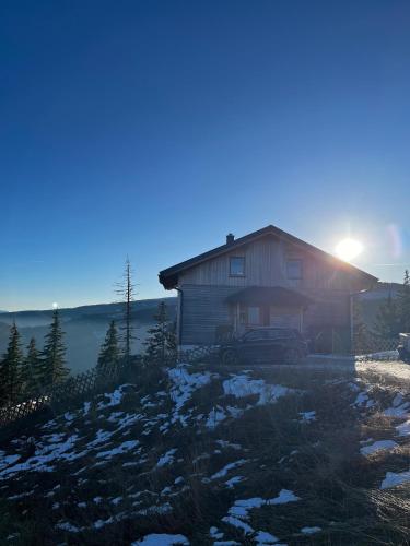 a house on a hill with the sun setting behind it at Almchalet Villa Diana in Klippitztorl