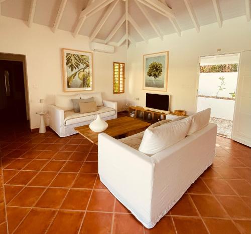 a living room with white couches and a tv at Villa Laucaly Orient Bay in Orient Bay