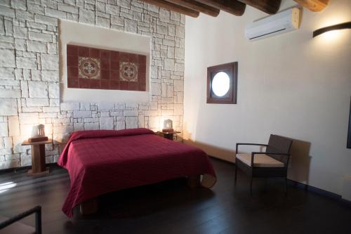 a bedroom with a red bed and a stone wall at I 5 SENSI in Marina di Modica
