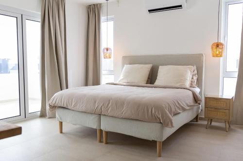 a white bedroom with a bed with white sheets and pillows at 3 bedroom luxury vacation villa for a relaxed intimate feeling in Willemstad