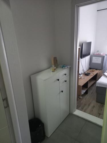 a room with a white cabinet and a desk with a computer at Hotel Duga in Novi Sad