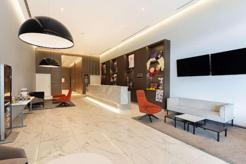 a lobby with orange chairs and a couch and tables at NH Monterrey La Fe in Monterrey
