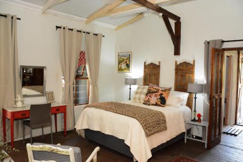 una camera da letto con un letto, una scrivania e un letto sidx sidx sidx di The Goat House Cottage a Wakkerstroom