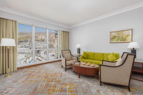 a living room with a yellow couch and chairs at Swissotel Al Maqam Makkah in Makkah