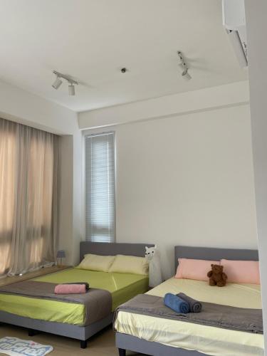Un dormitorio con dos camas y un osito de peluche sentado encima. en Sunway Grid Residence, Johor Bahru Homestay, en Iskandar Puteri