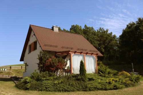 a small white house with a brown roof at Domki na Kaszubach - nad jeziorem z balią i sauną in Bytów