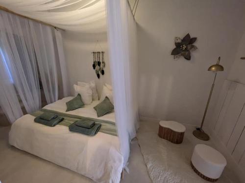 - une chambre avec un lit blanc et des oreillers verts dans l'établissement La Galatée, Balnéo et Sauna privatifs, à Saint-Saturnin-lès-Avignon