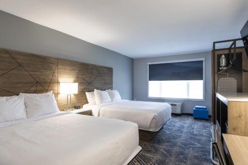 a hotel room with two beds and a flat screen tv at Rodeway Inn & Suites near Outlet Mall - Asheville in Asheville