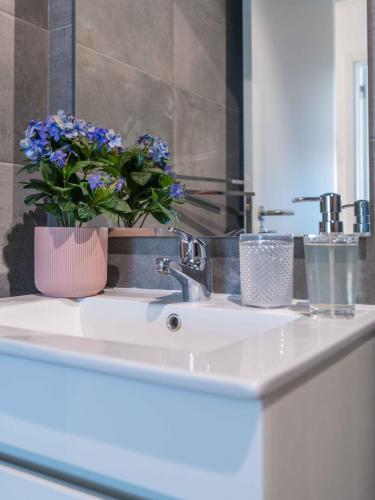 a bathroom sink with a vase of blue flowers on it at Caravelas 2-Bedroom Apartment with Pool - 50m from the Beach in Armação de Pêra