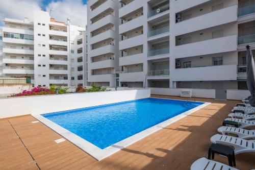 a swimming pool in front of a building at Caravelas 2-Bedroom Apartment with Pool - 50m from the Beach in Armação de Pêra