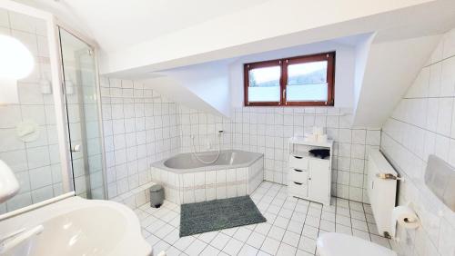 a white bathroom with a tub and a sink at Gemütliche Ferienwohnung in Bodenmais I Sauna I Balkon I Blick Silberberg in Bodenmais