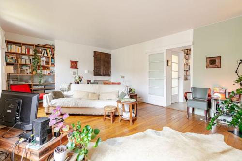 un salon avec un canapé blanc et une télévision dans l'établissement A paradise of calm and charm, à Paris