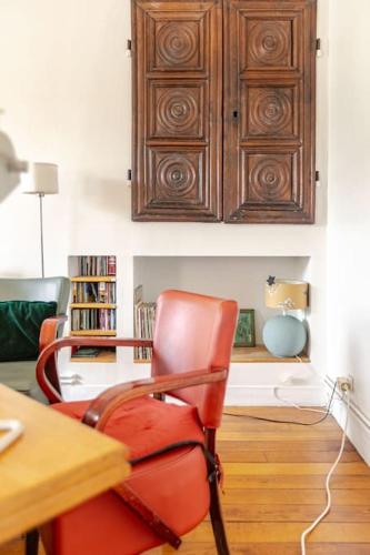 une chaise rouge dans une chambre avec une armoire en bois dans l'établissement A paradise of calm and charm, à Paris