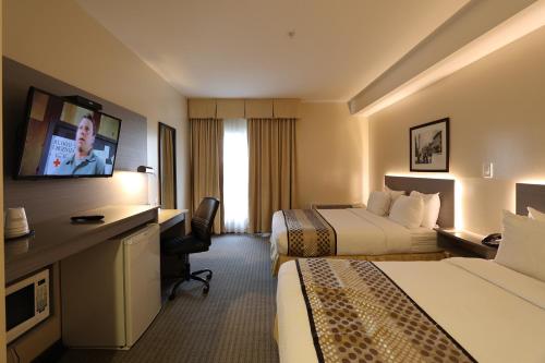 a hotel room with two beds and a flat screen tv at Days Inn by Wyndham Surrey in Surrey