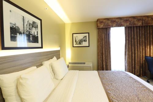 a bedroom with a bed with white pillows and a window at Days Inn by Wyndham Surrey in Surrey