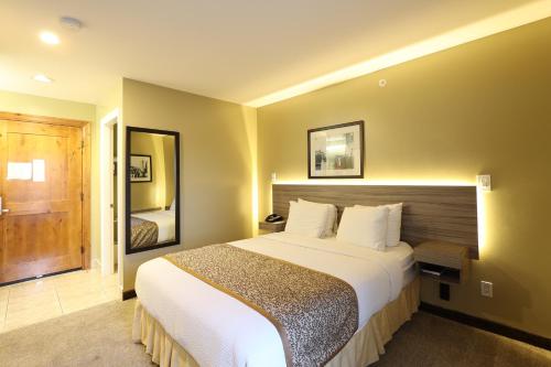a hotel room with a large bed and a mirror at Days Inn by Wyndham Surrey in Surrey