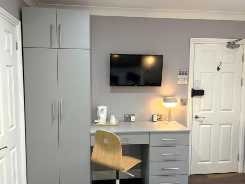 a desk with a chair and a tv on a wall at Melbury Rooms & Studios in Exeter