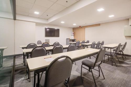 a conference room with tables and chairs and a screen at ibis budget Rio de Janeiro Nova America in Rio de Janeiro