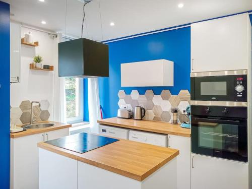 a kitchen with white cabinets and a blue wall at Kaliyan Appartements 4 in Hayange