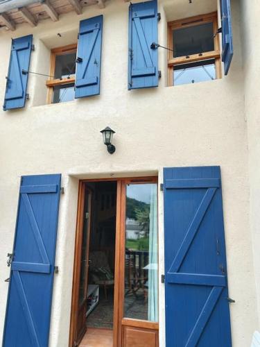 a building with blue doors and windows and a table at Les lits de Montbel gîte in Sonnac-sur-lʼHers