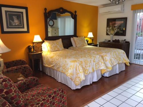 a bedroom with a bed and a chair and a mirror at Casa Larrea Inn in Palm Desert