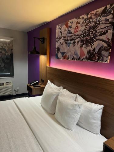 a bedroom with a bed with white pillows and a painting at La Quinta Inn by Wyndham Amarillo Mid-City in Amarillo
