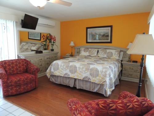 a bedroom with a bed and a chair at Casa Larrea Inn in Palm Desert