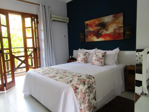 a bedroom with a white bed and a blue wall at Ilha flat Hotel Suíte Swaenen II in Ilhabela