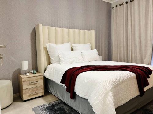 a bedroom with a large bed with a red blanket at Sunset Haven in Midrand