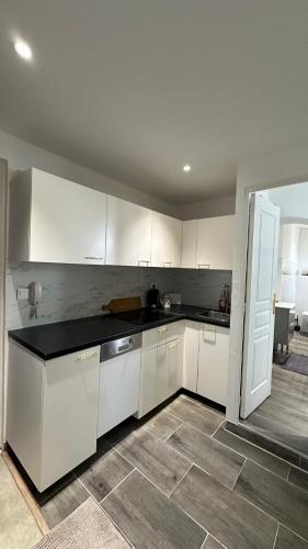 une cuisine avec des armoires blanches et un comptoir noir dans l'établissement Appartement neuf, centre-ville, 400m de rivetoile 6 voyageurs, à Strasbourg