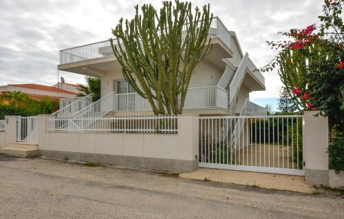 einen weißen Zaun vor einem Haus mit Kaktus in der Unterkunft Pet Friendly Apartment in Marina di Modica