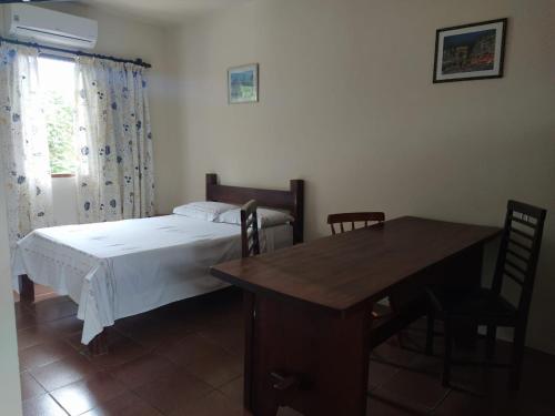 a bedroom with a bed and a table and a window at Chalés Xibayka Ilhabela in Ilhabela