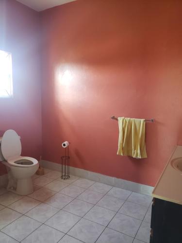 a bathroom with a toilet and a yellow towel on a wall at Montego Bay Guesthouse in Montego Bay