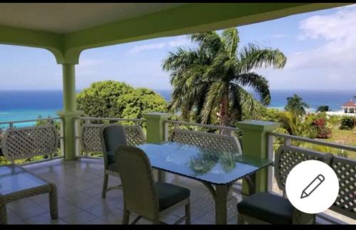a porch with a blue table and chairs and the ocean at Montego Bay Guesthouse in Montego Bay