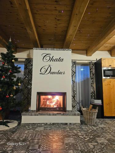 a fireplace in a living room with a christmas tree at Chata Ďumbier in Bystrá