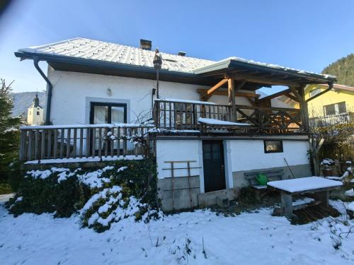 a house with a deck in the snow at Hiša Hortenzija Luče in Luče