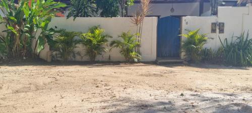 a fence with a blue door and some plants at Casa Recanto in Trancoso