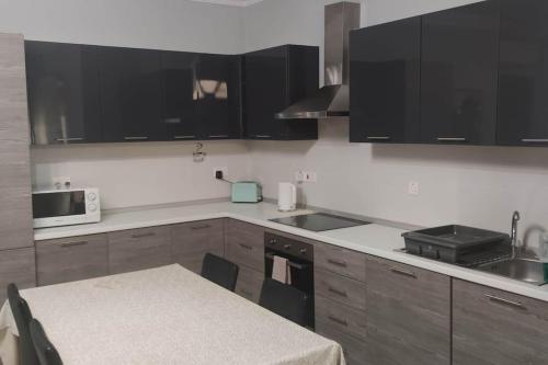 a kitchen with black cabinets and a table and a microwave at Cosy two bedroom maisonette in Xewkija