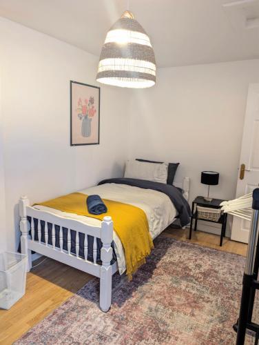 a bedroom with a bed with a yellow blanket at Ivy Townhouse Derry in Derry Londonderry