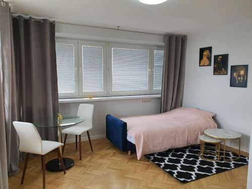 a bedroom with a bed and a table and chairs at Amazing View 19 floor! Metro Świętokrzyska in Warsaw
