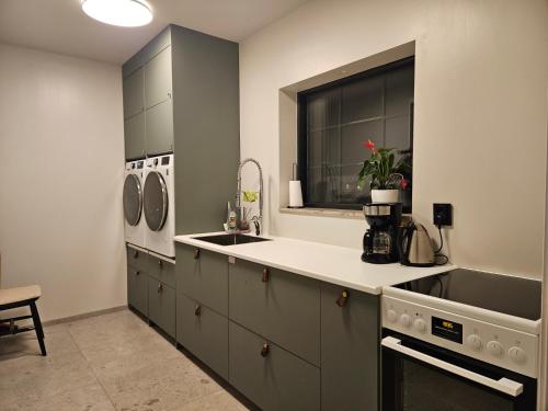 a kitchen with gray cabinets and a sink and a window at Egen del av modern villa i Kåge in Skellefteå