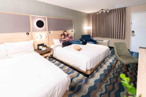 a woman sitting on a bed in a hotel room at Accent Inns Kelowna in Kelowna