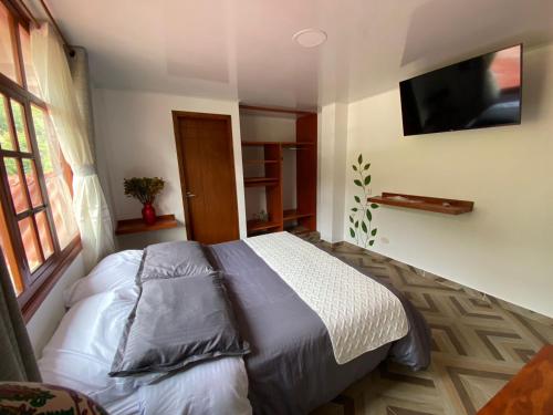 a bedroom with a bed and a flat screen tv at ocobos club campestre in Tibirita