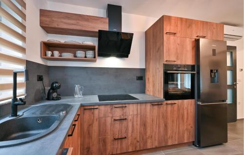a kitchen with wooden cabinets and a stainless steel refrigerator at Stunning Home In Vinogradi Ludbreski in Vinogradi Ludbreški