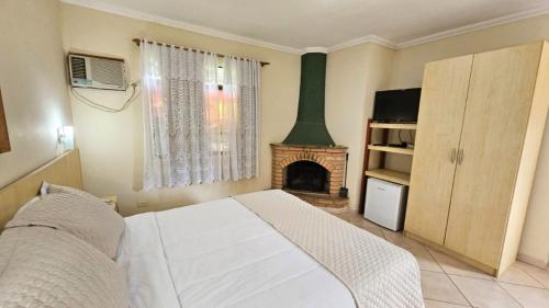 a bedroom with a white bed and a fireplace at Vila Francesa Hotel in Penedo