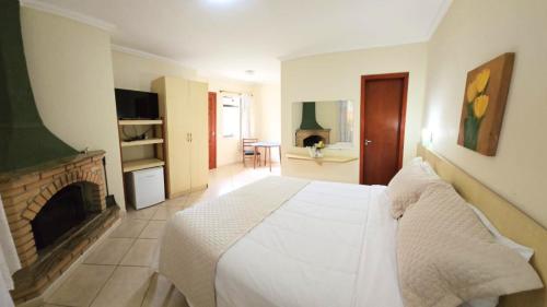 a bedroom with a white bed and a fireplace at Vila Francesa Hotel in Penedo