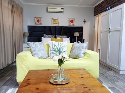 a yellow couch in a living room with a table at Devine Stay- Pmb in Pietermaritzburg
