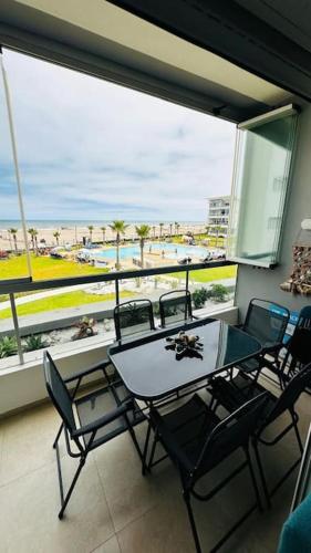 Una mesa y sillas en un balcón con vista a la playa. en Sidi Rahal Front mer, piscine & accès direct plage, en Dar Oulad Hajj Kassem