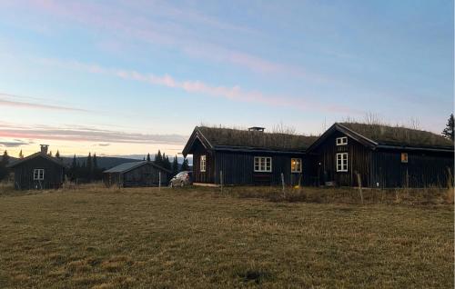 a black house in a field next to a field at Cozy Home In Fåvang With Wifi in Favang