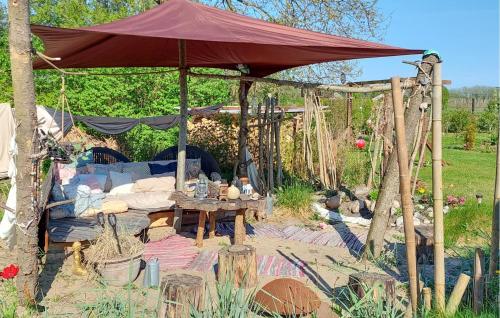 a large red umbrella in a garden with a table at 3 Bedroom Cozy Home In Nibe in Nibe